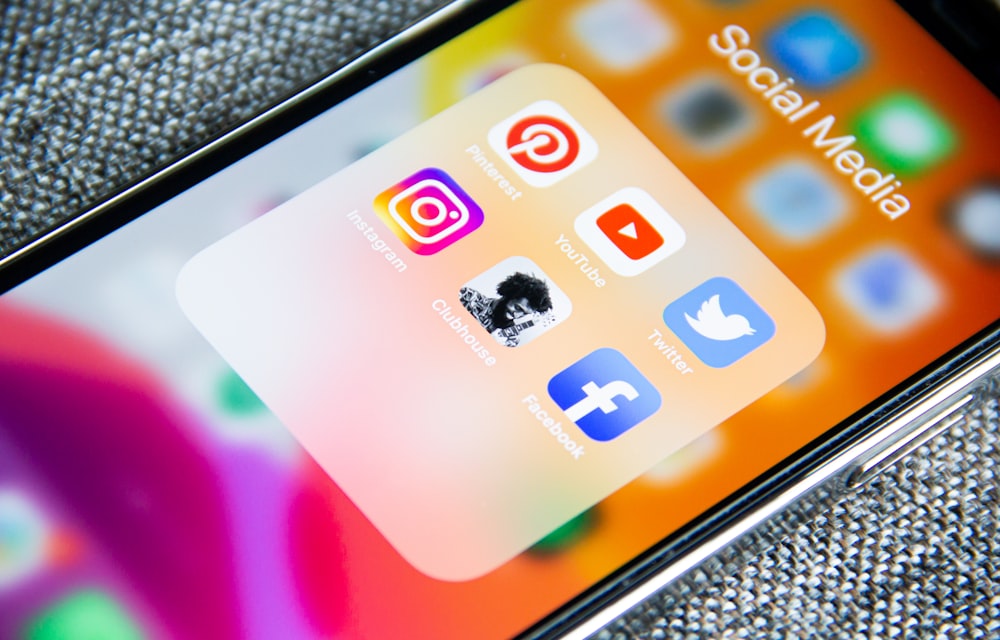 A smartphone home screen showing a folder of social and video apps including YouTube, Instagram, Facebook and X